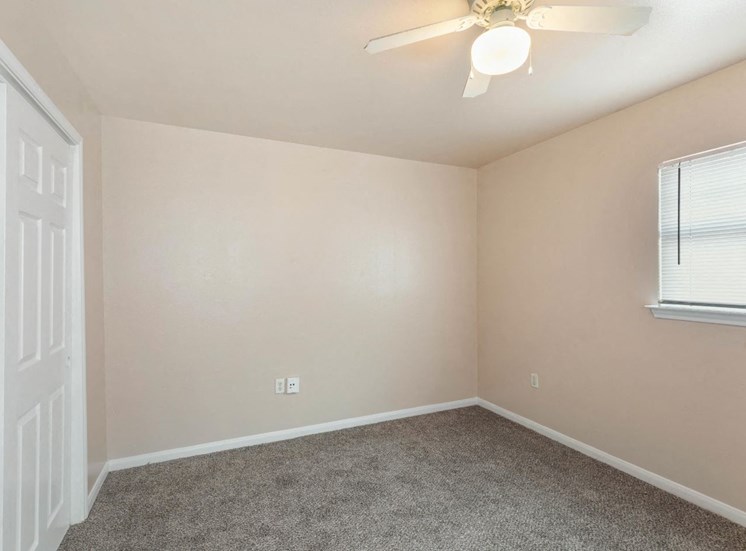 Bedroom with wall to wall carpet, ceiling fan, and white trim.